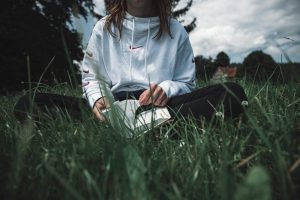 woman in white long sleeve shirt sitting on green grass field during daytime